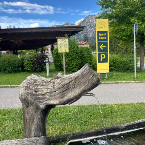 Water flowing into a wooden trough, with a sign for Guest House P