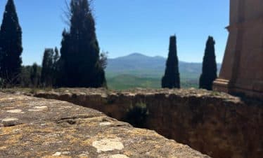 Stone wall with Tuscan landscape, cypress trees, and mountains in background
